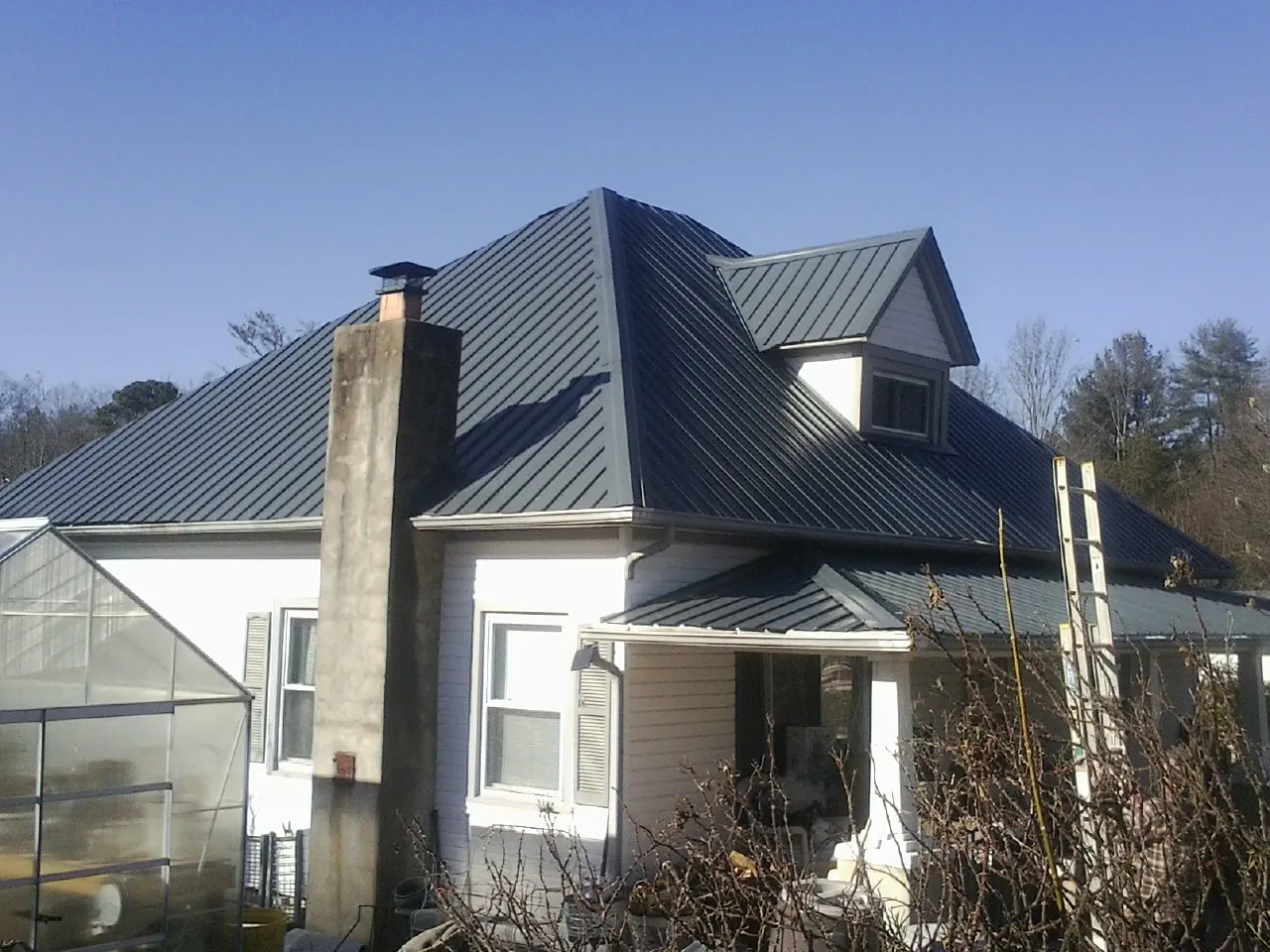 Dark blue standing seam metal roof on a white farmhouse with dormer — Slate & Tile Roof Repair by Roofing Brothers in Medusa
