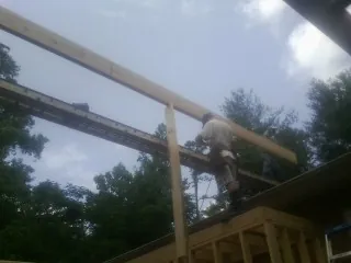 Carpenter setting a ridge beam over a new addition frame — Ice Dam Removal by Roofing Brothers in Medusa