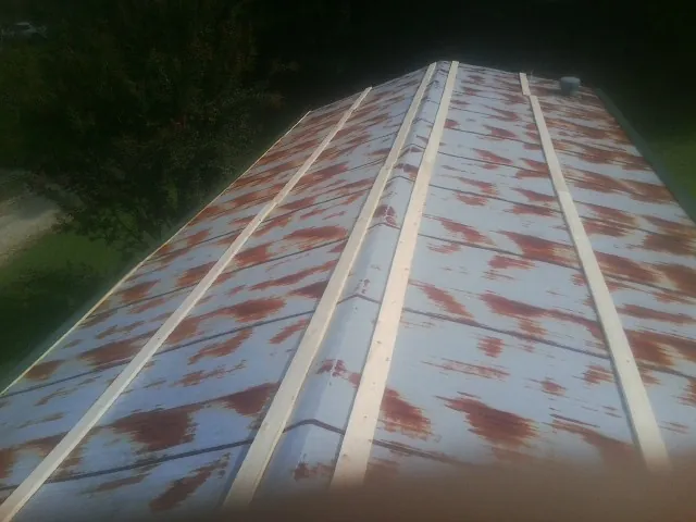 Rusted metal roof panels with new wood purlins before replacement in Medusa
