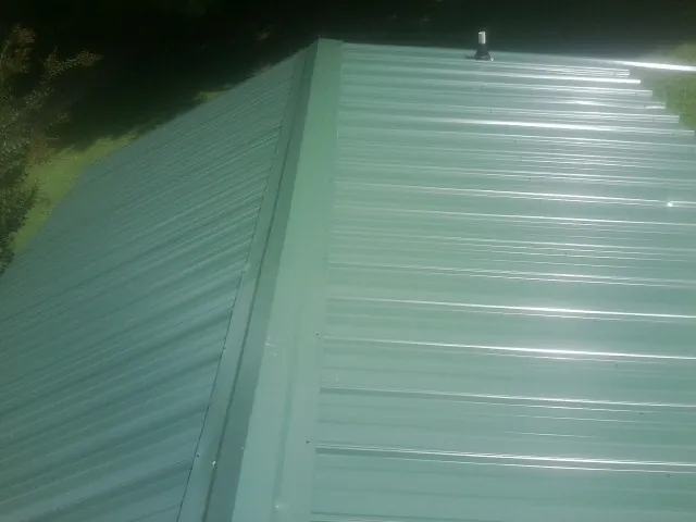 New green metal panels meeting at the ridge of a roof — Flat Roof Repair work by our crew in Medusa