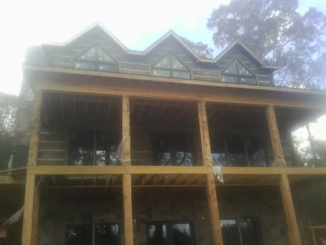 Dormers and porch framing on a large log home under construction — Roof Coating work by our crew in Medusa