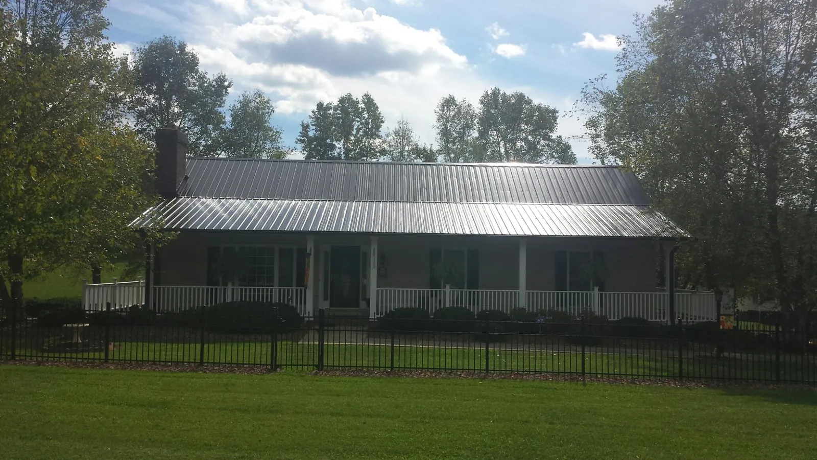 Gray metal roof on a brick ranch with a full width front porch — Gutter Guard Installation work by our crew in Medusa