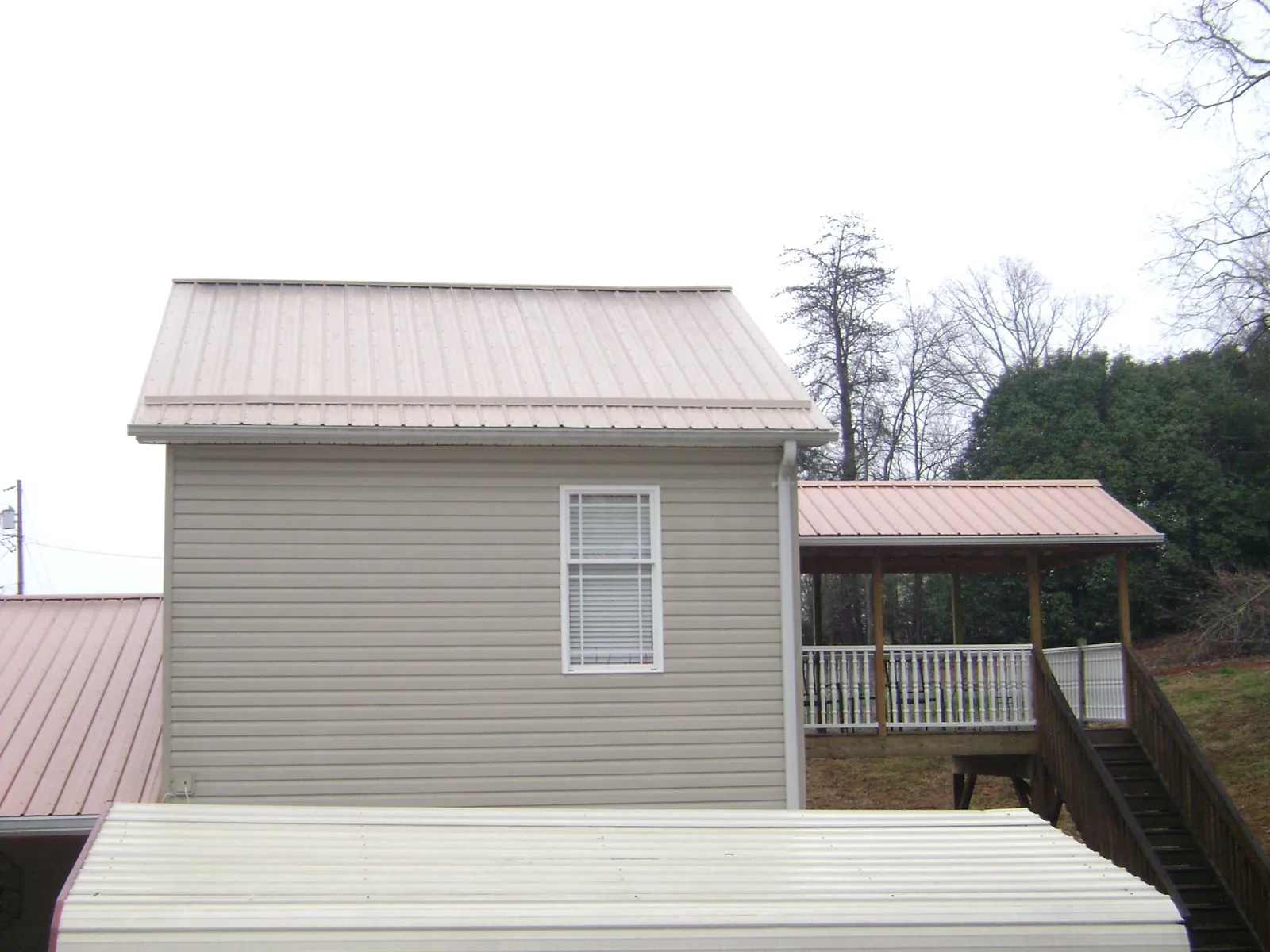 Tan metal roofs on a two story addition and attached porch, from a Roof Replacement job in Medusa