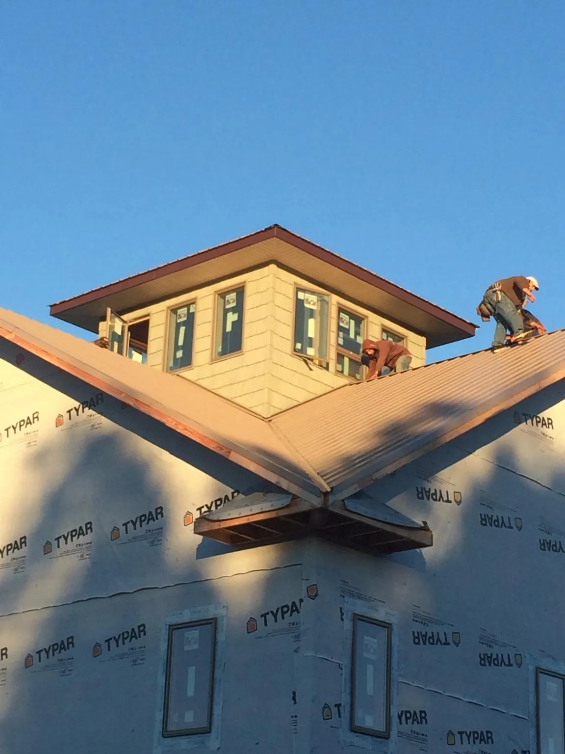 Roofers working around a rooftop cupola on a new metal roof at sunset — Roof Waterproofing in Medusa by Roofing Brothers